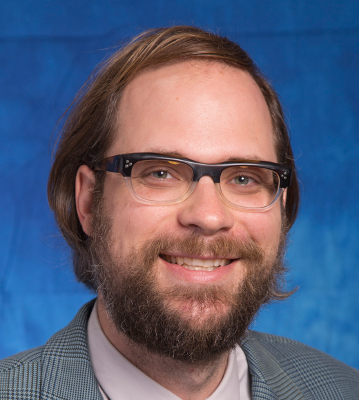 A professional headshot of Dr. Bradley Ander. He is a fair-skinned man with brown hair, glasses, a mustache, and beard.